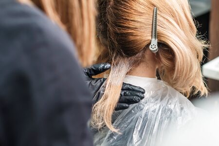 Hair dyeing of young woman by hands of hairstylist close up.の写真素材