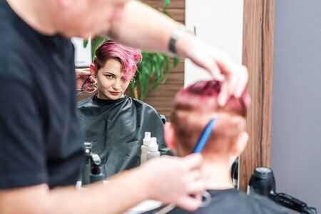 Hairdresser combs hair of woman at hair salon.の写真素材