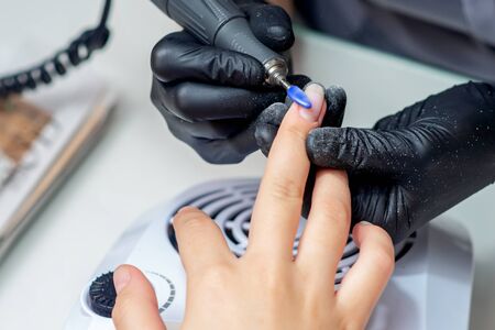 Manicure master removing nail polish in beauty salon with special electric machine.の写真素材