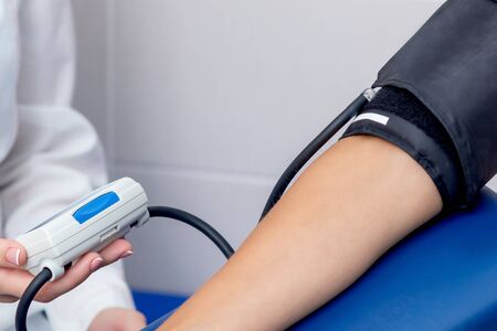 Doctor measures the pressure of young woman close up.