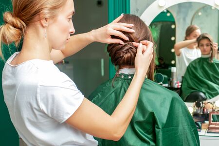 Hairdresser is making hairstyle of woman in beauty salon.の写真素材
