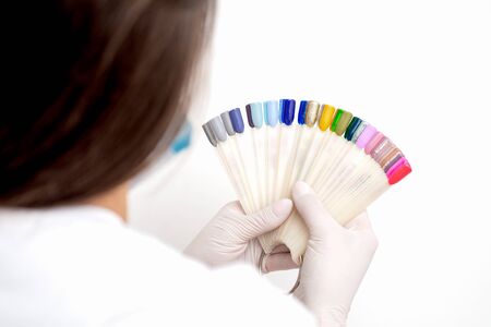 Manicure master holding manicure nail color samples palette on white background.の写真素材
