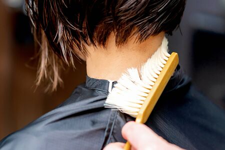 Hand os hairdresser is cleaning neck with brush from cutted hair after haircut.