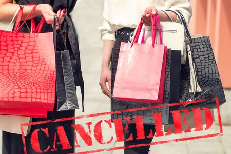 Word CANCELLED on background of two young women in the shopping mall. Coronavirus quarantine. Closed...