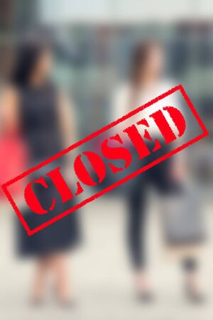 Word CLOSED on background of two young women in the shopping mall. Coronavirus quarantine. Closed...
