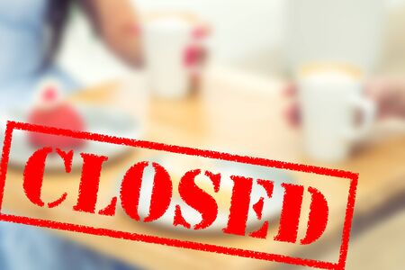 Word CLOSED on blurred background of two young women in the cafe outdoors. Coronavirus quarantine. Closed cafe outdoors.の写真素材