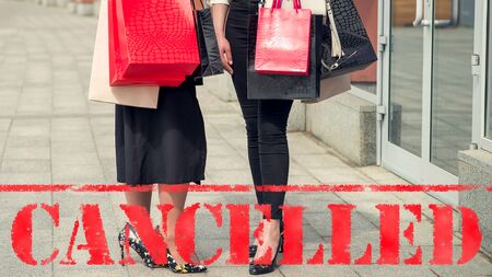 Word CANCELLED on background of two young women in the shopping mall. Coronavirus quarantine. Closed...
