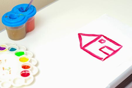 Children's artwork. Children's drawing of simple red house by watercolors on white sheet of paper.の写真素材