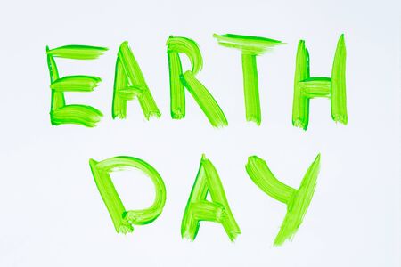 Top view of words Earth Day painted by green watercolor on white sheet of paper.の写真素材