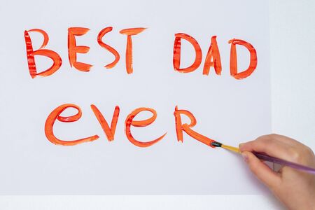 Top view of hand of child drawing handwritten text Best Dad Ever on white paper. Happy Father's Day and family concept.の写真素材