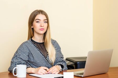 Portrait of a casual business woman sitting at her workplace in home office.の写真素材