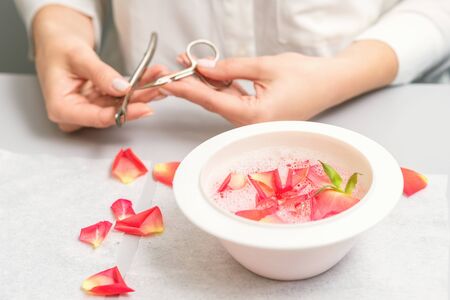 Pink petals in bowl with pure water on white table in beauty spa manicure salon.の写真素材