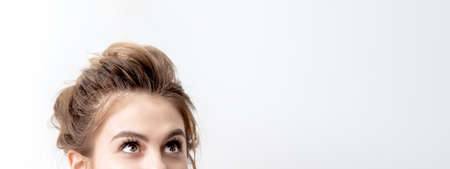 Half face of beautiful young caucasian woman looking up on white background. Girl looking upwards with copy spaceの写真素材