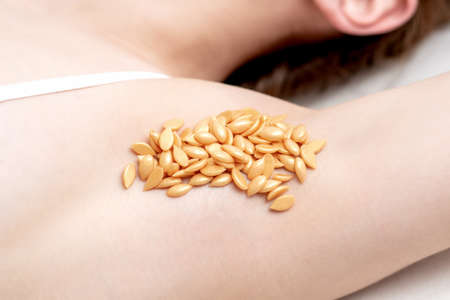 Wax orange beans on armpit of young caucasian woman. Depilation concept