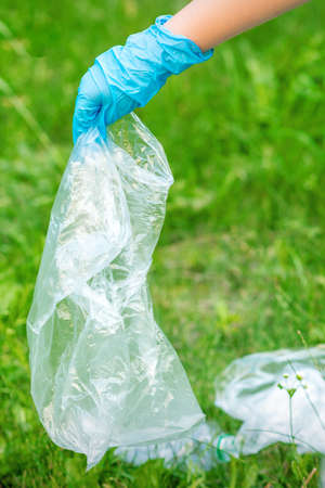 Hand of child cleans the park from plastic debris lying on the green grassの写真素材