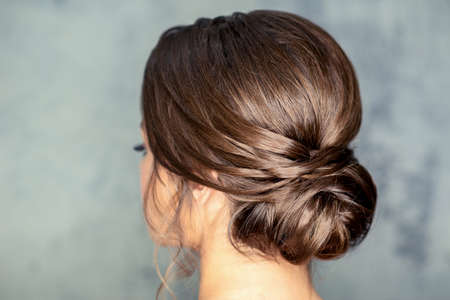 Rear view of young brunette woman with beautiful middle bun hairstyle on gray backgroundの写真素材