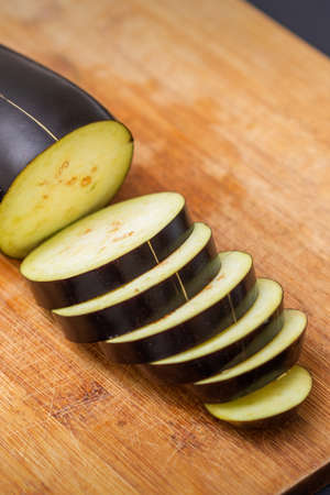 Fresh sliced eggplant on wooden cutting board isolated on black. Cooking ingredientsの写真素材