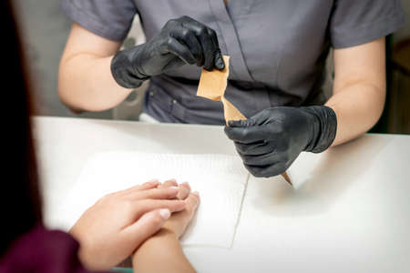 Manicure master opening craft envelope with manicure tools in nail salon