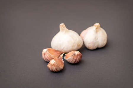 Still life of two garlic heads and garlic cloves grouped on dark backgroundの写真素材