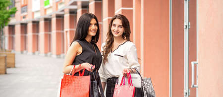Portrait of two beautiful young caucasian girfriends with shopping bags near the mallの写真素材