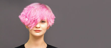 Portrait of fashion model young woman with stylish dyed pink hair in black clothes on dark...