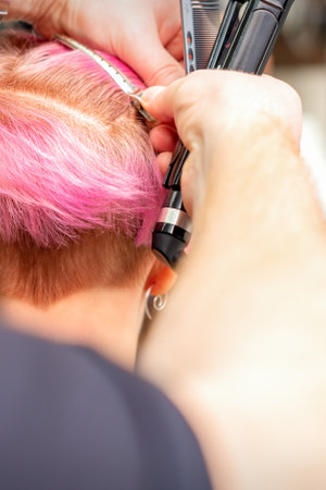 Hairdresser pinches hair with the clip before doing hairstyle in a hair salonの写真素材