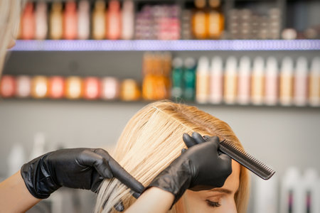 Hairdressers hand combs female hair before dyeing in a beauty salonの写真素材