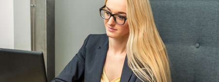 Young businesswoman using laptop sitting at the table in a cafeの写真素材