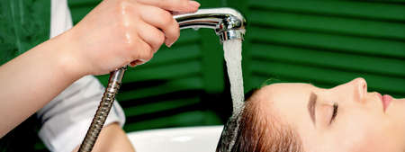 Side view photo of a young caucasian woman receiving washing hair in a hair salon