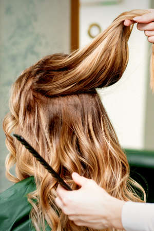 Hairdresser holds a strand of long hair of a young woman in a beauty salonの写真素材