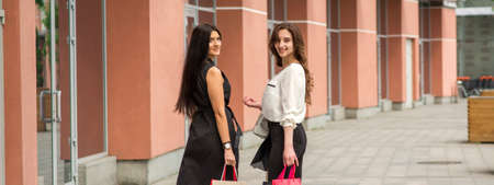 Two beautiful young caucasian happy women with shopping bags walk into the shopping mallの写真素材