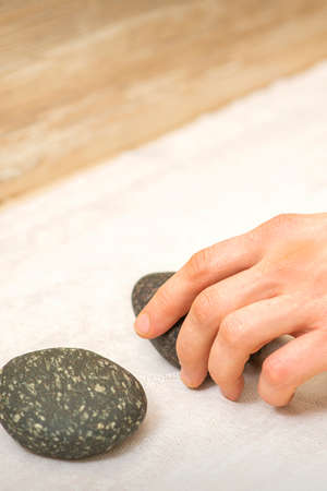 Hand of massage therapist taking massage stones from the table before massage procedures