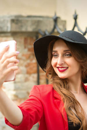 Beautiful smiling caucasian young woman taking selfie on the smartphone against an urban backgroundの写真素材