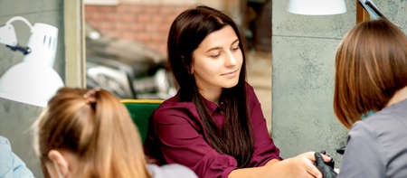Beautiful young caucasian woman receiving nail treatment sitting in a beauty nail salonの写真素材