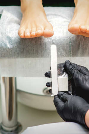 Nail file tool in hands of chiropodist before procedure files nails on toes in a nail salonの写真素材