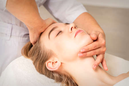 Young caucasian woman receiving a head and chin massage in a spa medical center