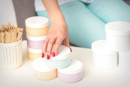 Beauticians hand takes jar with cosmetics from table offering and selling cosmetic products, moisturizing cream, wax pasteの写真素材