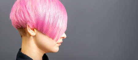 Profile portrait of a young caucasian woman with pink bob haircut isolated on a gray background, copy spaceの写真素材
