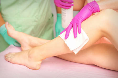 Master of depilation wipes female feet with white napkin preparing for the procedure of hair removalの写真素材