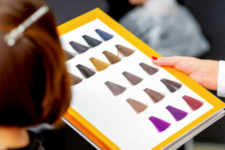 Young caucasian woman choosing a color from the hair color chart in a beauty salonの写真素材