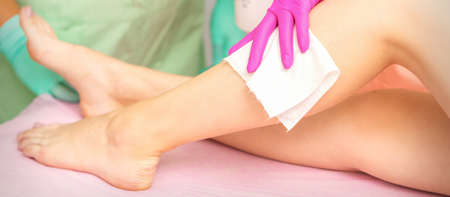 Master of depilation wipes female feet with white napkin preparing for the procedure of hair removalの写真素材