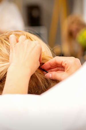 Hair stylists hands doing professional hairstyling of female long hair in a beauty salonの写真素材