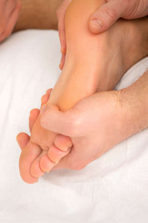 Relaxing double massage on the female foot by two masseurs in spa salonの写真素材