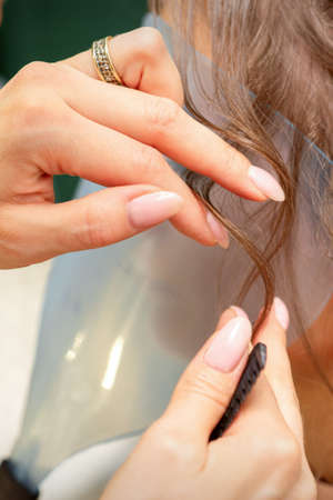 Close Up hairdresser stylist makes hairstyle for a young woman in a beauty salonの写真素材