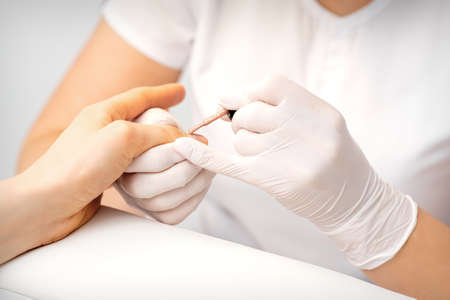 Young woman receiving pink or beige nail polish in a beauty salonの写真素材
