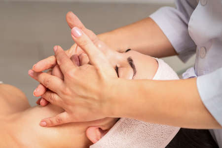 Beautiful caucasian young woman getting a facial massage at a beauty salonの写真素材