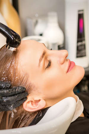 Young caucasian blonde woman having hair washed in the sink at a beauty salonの写真素材