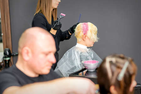 Coloring female hair in the hair salon. Young woman having her hair dyed by beautician at the beauty parlorの写真素材