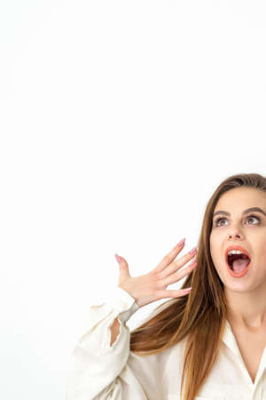Shocked young caucasian woman with open mouth looking up and expresses surprise isolated over white...
