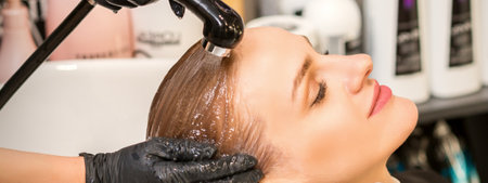 Young caucasian blonde woman having hair washed in the sink at a beauty salonの写真素材